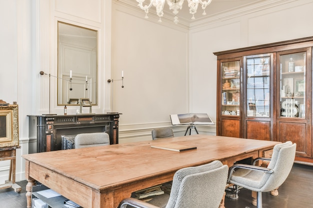 Klassisches Interieur des Villenarbeitsraums mit Holztisch und Schrank und Kamin unter Kronleuchter