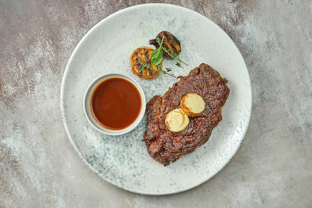 Klassisches Rindersteak mit würziger Butter und Soße in einem Teller. Nahaufnahme, selektiver Fokus