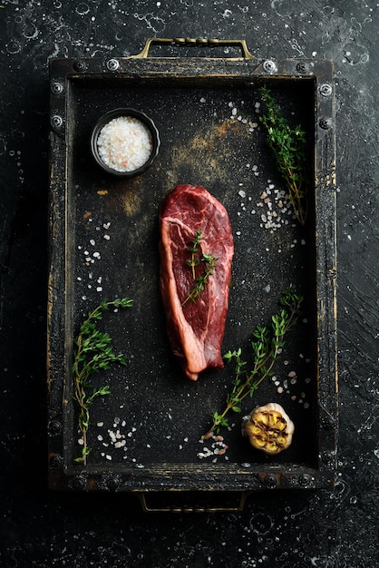 Klassisches rohes Roastbeef-Steak Frisches Fleisch mit Gewürzen Altes Steak Draufsicht Auf einem schwarzen Steinhintergrund