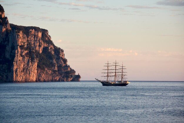 Foto klassisches segelboot, das bei sonnenaufgang in der bucht verankert ist