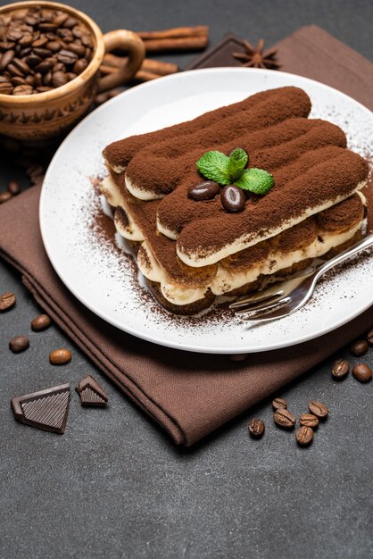 Klassisches Tiramisu-Dessert auf einer Keramikplatte auf dunklem Betonhintergrund