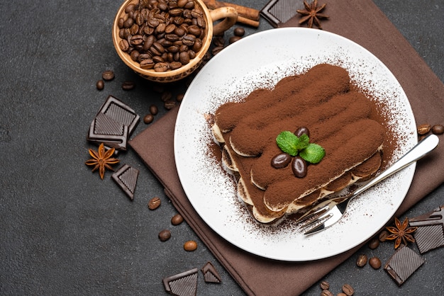 Klassisches tiramisu-dessert auf einer keramikplatte auf dunklem betonhintergrund