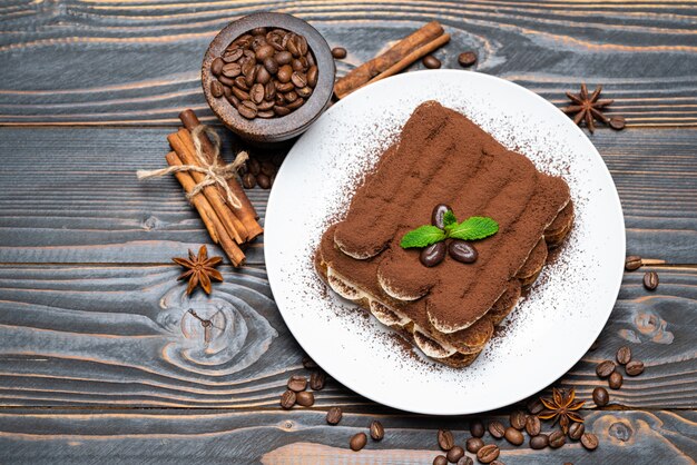 Klassisches Tiramisu-Dessert auf Keramikplatte auf hölzernem Hintergrund