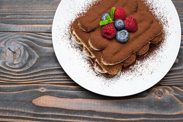 Klassisches Tiramisu-Dessert mit Himbeeren und Blaubeeren auf einem Keramikteller