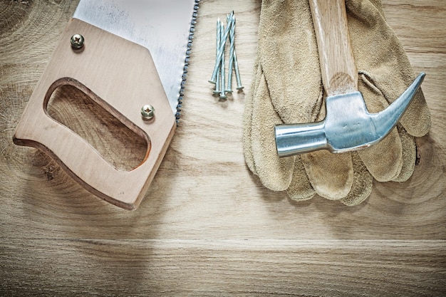 Klauenhammer-Lederschutzhandschuhe Handsägenägel auf Holzbrett-Konstruktionskonzept