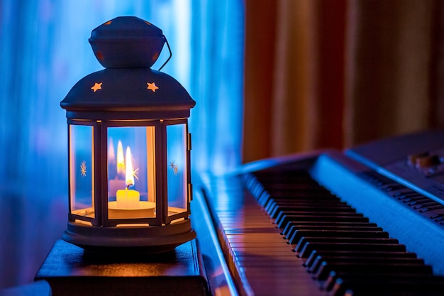 Klavier im Licht einer Laterne mit einer Kerze gegen das Fenster am Abend