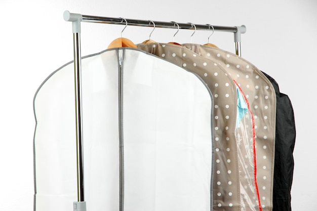 Kleidung in Kisten zum Aufbewahren auf Kleiderbügeln auf grauem Hintergrund