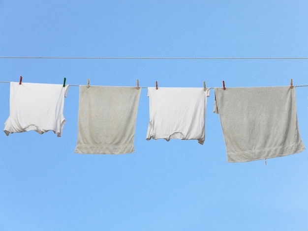 Foto kleidung trocknet auf der wäscheleine gegen den klaren blauen himmel