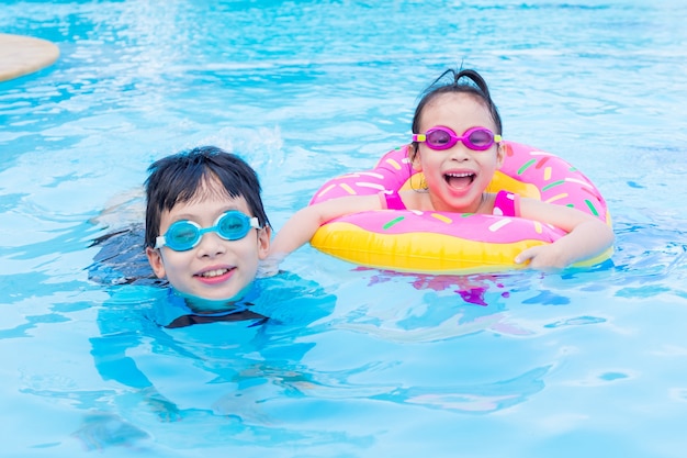 Kleine asiatische Geschwister glücklich zusammen im Swimmingpool