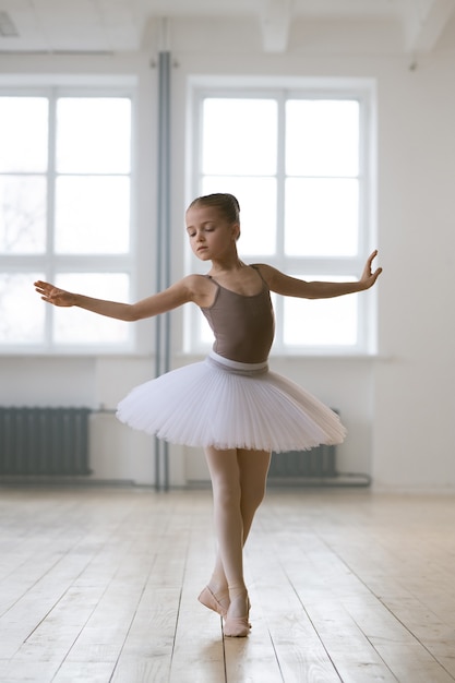 Kleine Ballerina im Tutukleid übt Ballett im Tanzstudio