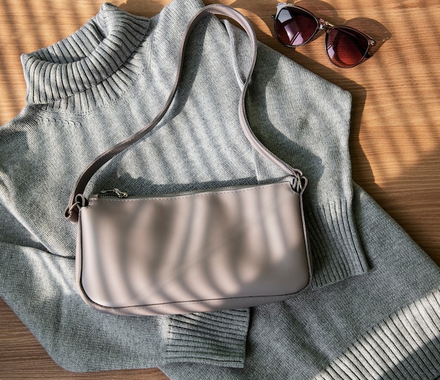 Kleine beige Ledertasche und grauer Pullover