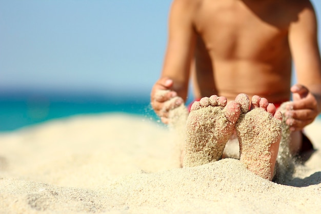 Kleine Beine eines Kindes auf dem Sand am Strand