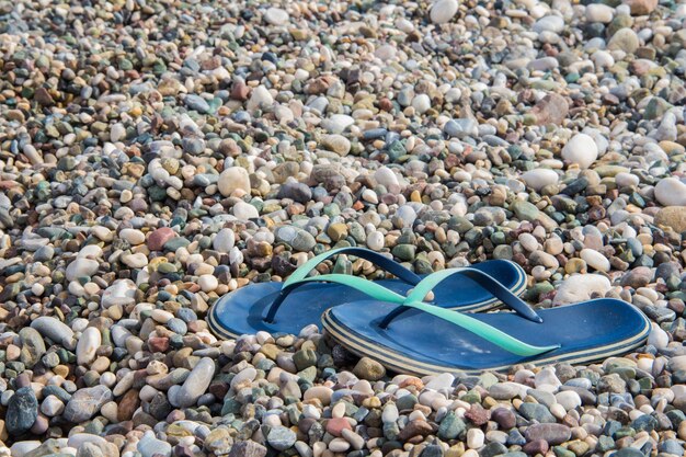 Foto kleine bunte kieselsteine und pantoffeln strandpantoffeln auf dem hintergrund von kleinen muscheln