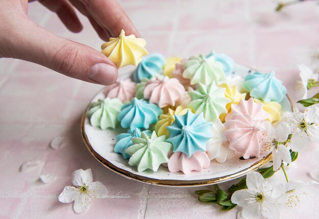 Kleine bunte Meringues in der Keramikplatte auf rosa Fliesen-Hintergrund