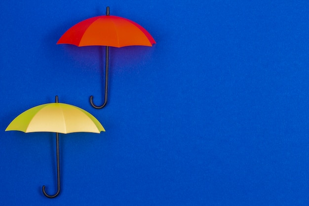 Kleine bunte Regenschirme auf blauem Farbhintergrund