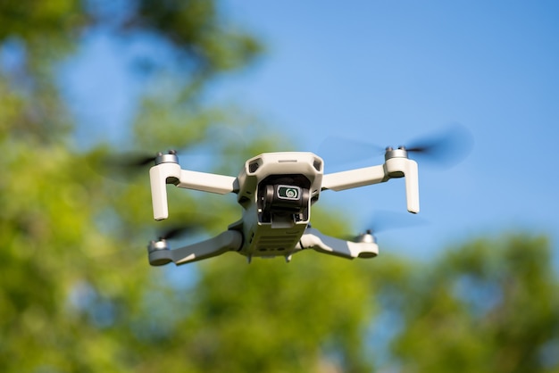 Kleine Drohne fliegt in der Luft mit Bäumen am