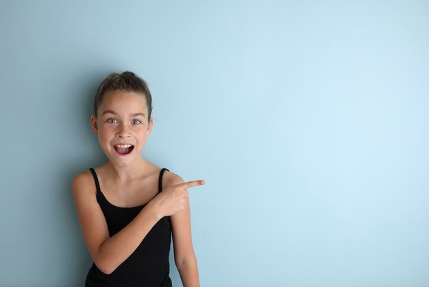 Kleine emotionale Teenager-Mädchen in einem schwarzen T-Shirt 11 12 Jahre alt auf einem isolierten blauen Hintergrund Children39s Studioportrait Platzieren Sie den Text, um den Platz für die Inschrift zu kopieren