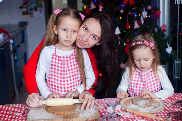 Kleine entzückende Mädchen und junge Mutter, die Weihnachtslebkuchenplätzchen backen