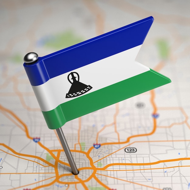 Kleine Flagge Königreich Lesotho auf einem Kartenhintergrund mit selektivem Fokus.