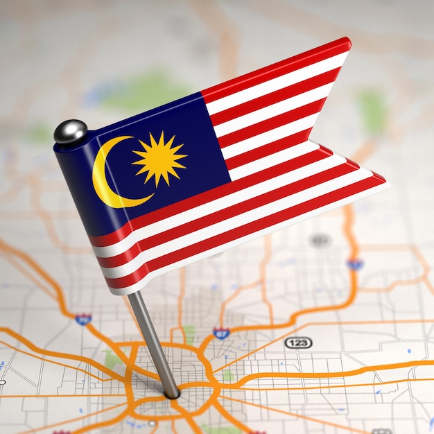 Kleine Flagge von Malaysia klebte im Kartenhintergrund mit selektivem Fokus.