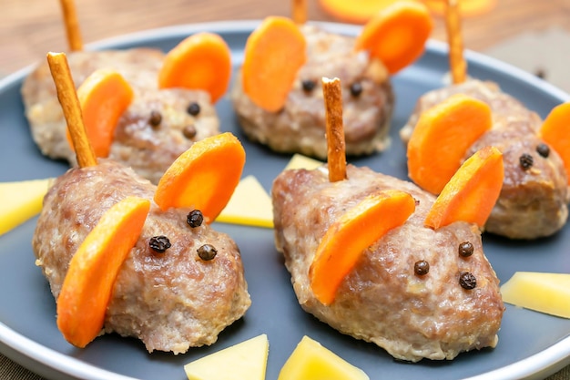 Kleine Fleischbällchen-Maus-Hackbraten-Mäuse mit Ohren von Karottenkäse auf Teller kreative und unterhaltsame Imbiss-Idee für Kinderparty Menü für gruselige Halloween-Dessert-Leckereien essbare süße Ratte selektiver Fokus