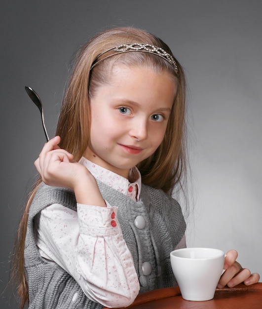 Kleine Frau mit Tasse Tee, die einen Löffel in der Hand hält