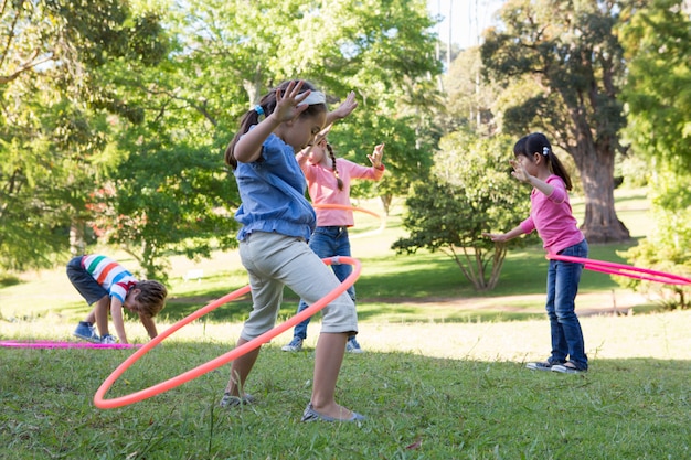 Kleine Freunde, die mit hula Bändern im Park spielen
