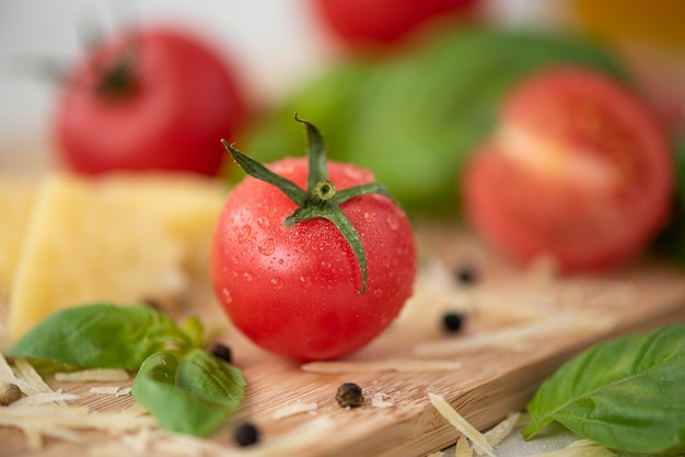 Kleine frische rosa Tomaten mit Basilikum-Nahaufnahme