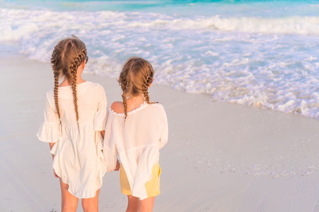 Kleine fröhliche lustige Mädchen haben viel Spaß am tropischen Strand, wenn sie zusammen spielen.