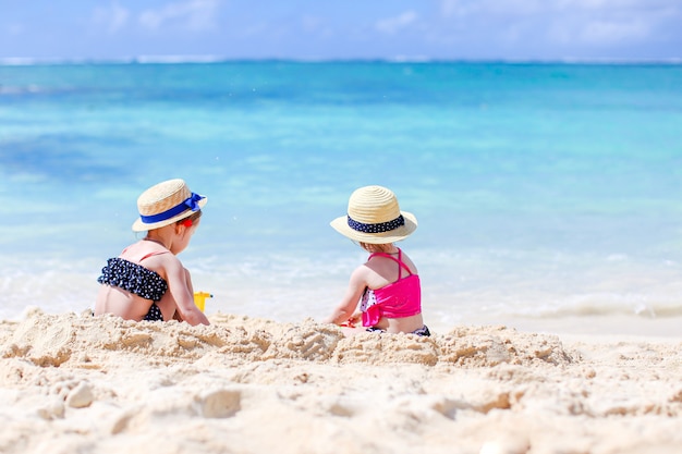 Kleine fröhliche lustige Mädchen haben viel Spaß am tropischen Strand, wenn sie zusammen spielen.