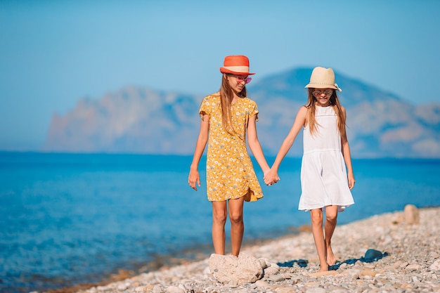 Kleine fröhliche lustige Mädchen haben viel Spaß am tropischen Strand, wenn sie zusammen spielen