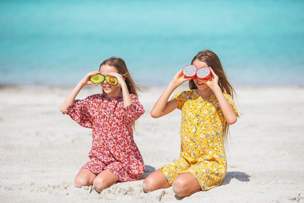 Kleine fröhliche lustige Mädchen haben viel Spaß am tropischen Strand, wenn sie zusammen spielen