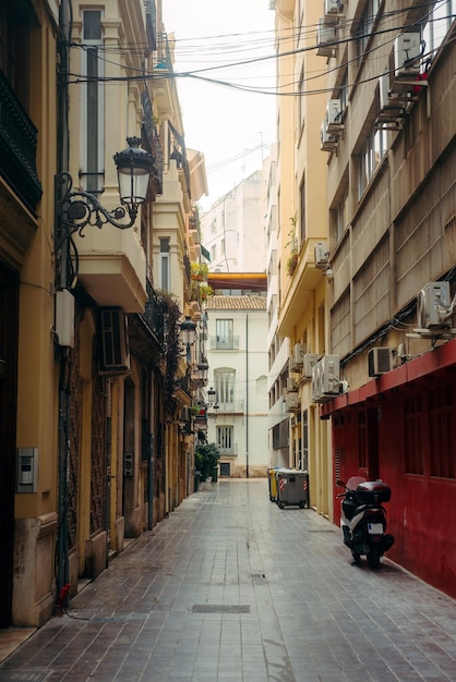 Kleine gepflasterte Straße einer europäischen Stadt mit Balkonpflanzen und einem Motorroller