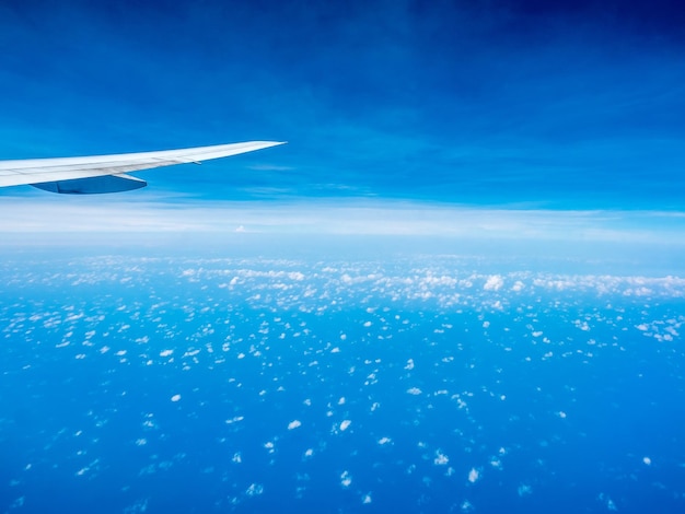 Kleine geschwollene Wolke am blauen Himmel mit Flugzeugflügel aus Flugzeugfensteransicht