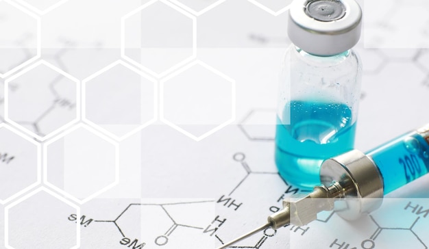 Kleine Gläser mit Injektion und Spritze zur Injektion auf blauem Hintergrund in der Nähe der chemischen Formel