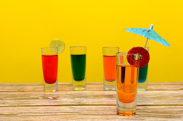 Foto kleine glasgläser mit bunten getränken auf holztisch