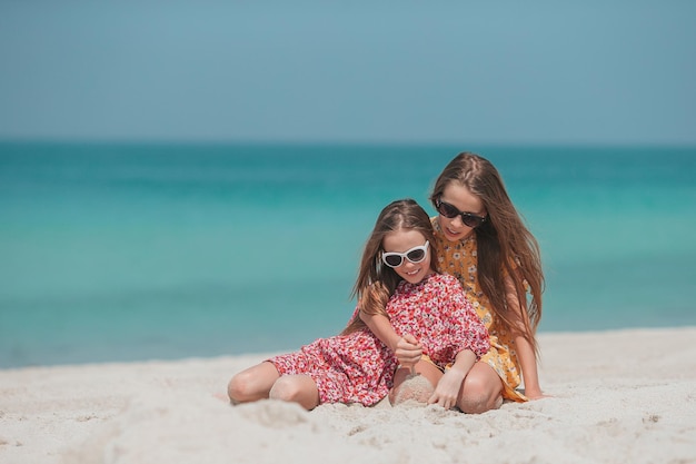 Kleine glückliche lustige Mädchen haben viel Spaß am tropischen Strand, der zusammen spielt