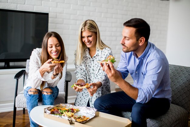 Kleine Gruppe junge Freunde, die Pizza im Raum essen