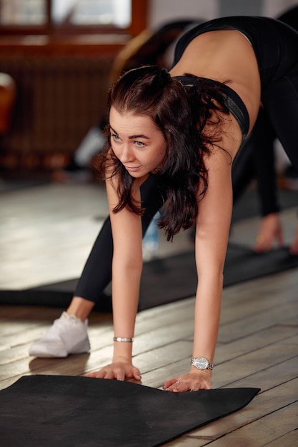 Kleine Gruppe von Menschen mit gesunden Gewohnheiten, die Dehnübungen auf dem Boden eines Fitnessstudios machen Selektiver Fokus auf Brunet-Frau