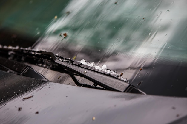 Kleine Hageleiskugeln auf schwarzer Motorhaube nach schwerem Sommersturm