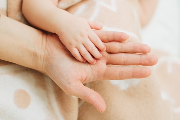 Kleine Hand eines Neugeborenen in der Hand eines Erwachsenen.