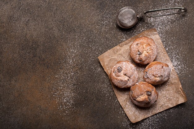 Kleine hausgemachte Muffins mit Schokolade und Rosinen auf einem Holztisch, Draufsicht