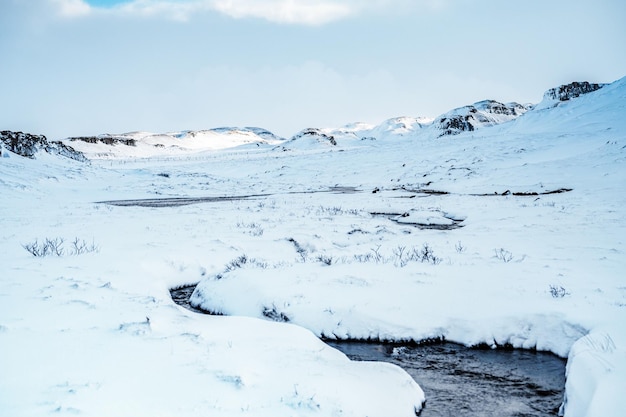 Kleine heiße Quelle in Hrunalaug Winter Island Baden in einer heißen Quelle unter freiem Himmel mit herrlichem Blick auf die schneebedeckten Berge