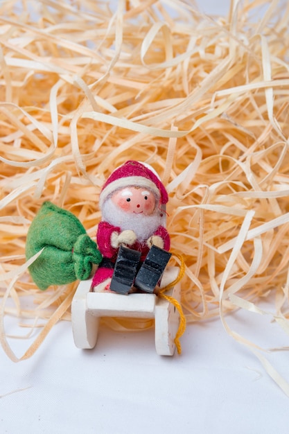 Kleine hölzerne Weihnachtsmann auf weißem Hintergrund mit Stroh im Hintergrund In Rio De Janeiro.