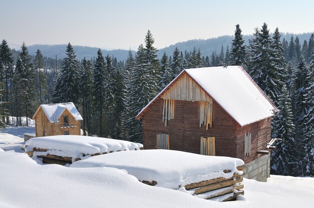 Kleine Holzhäuser auf einem schönen schneebedeckten Bergwald. Waldhaus mit Schnee bedeckt