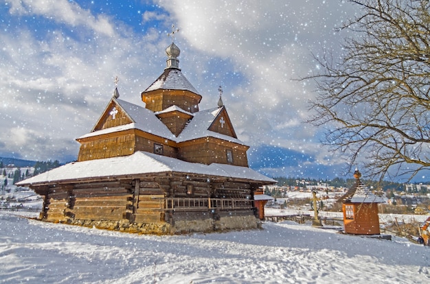 Kleine Holzkirche. Heiligabend bei Schneefall, alte Volksarchitektur. Wallpaper mit Silvesterstimmung