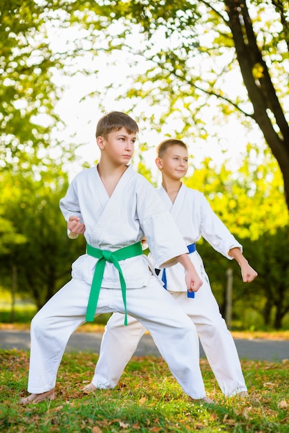 Kleine Jungen im weißen Kimono während des Trainings Karateübungen im Sommer im Freien