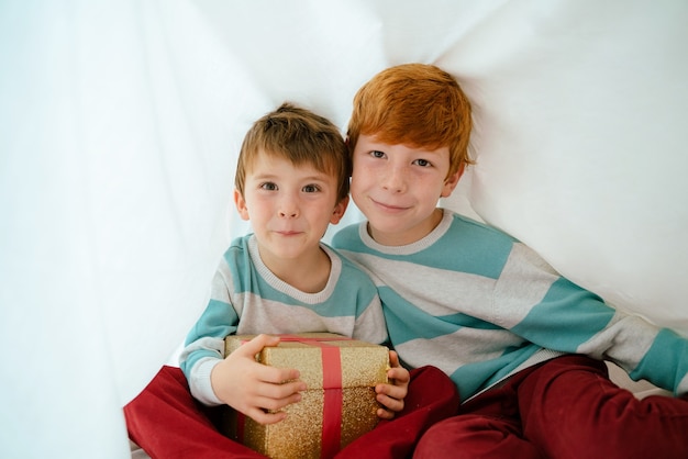 Kleine Jungen zu Hause am Weihnachtsmorgen mit Geschenk