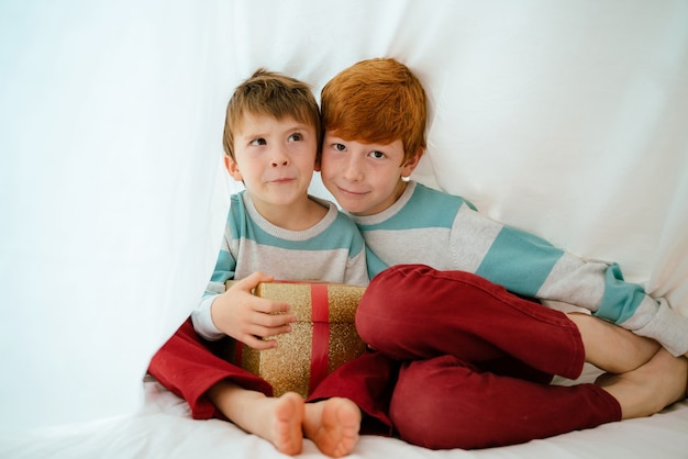 Kleine Jungen zu Hause am Weihnachtsmorgen mit Geschenk