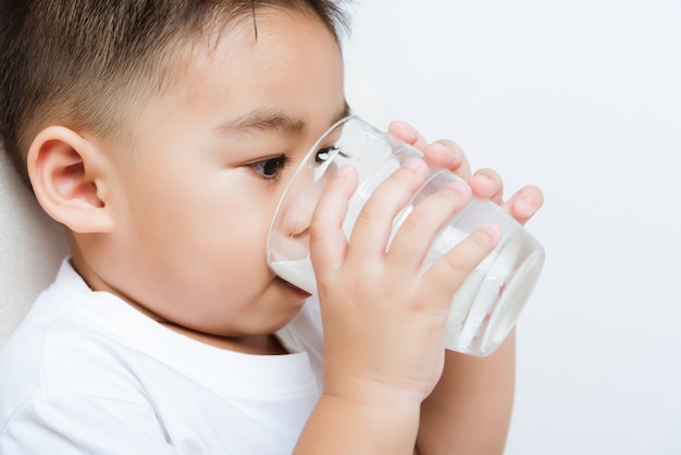 kleine Jungenhand, die Milchglas hält, während er weiße Milch trinkt